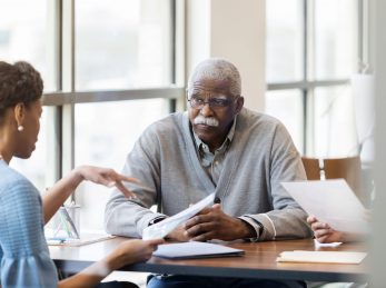 Female loan officer talks with senior man A senior African American man speaking with a loan officer