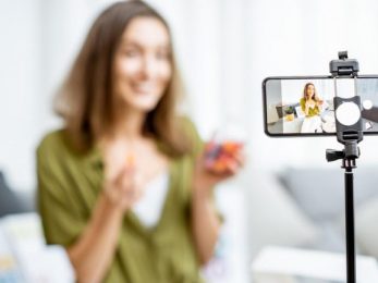 A woman recording a video with her phone on a tripod